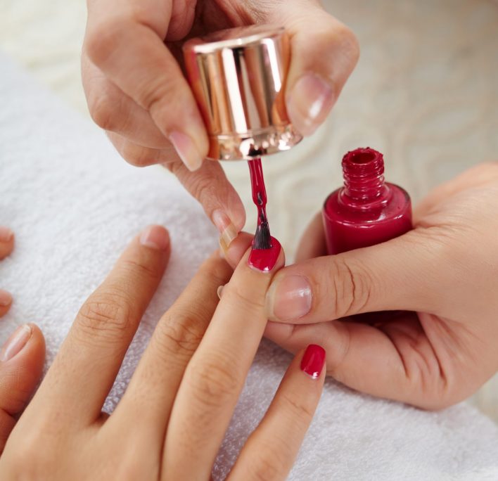 Bright manicure Master applying bright color to nails of woman